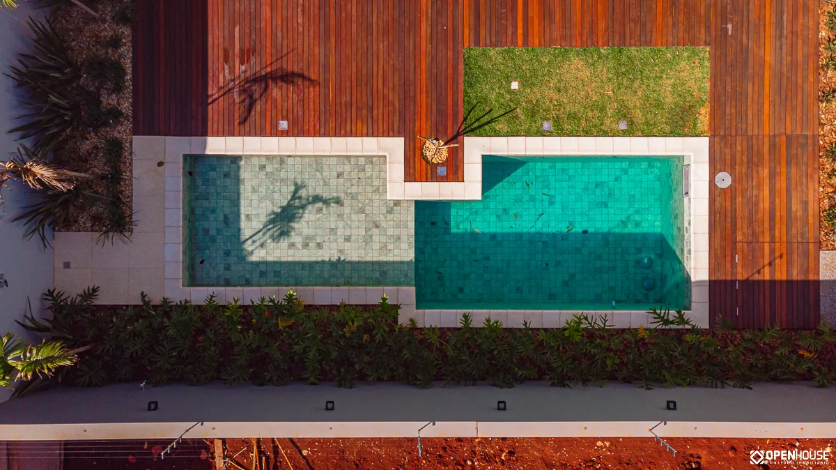 Vista aérea vertical revelando a geometria retangular articulada da piscina e da área rasa