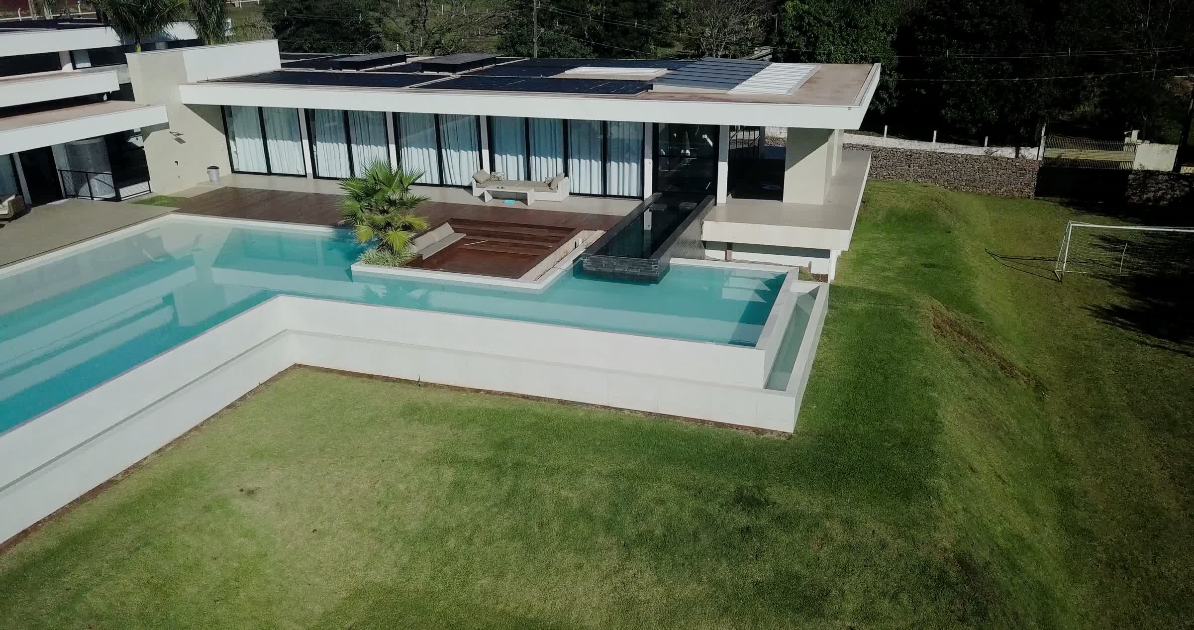 Vista aérea de piscina residencial com borda infinita integrada à arquitetura da casa