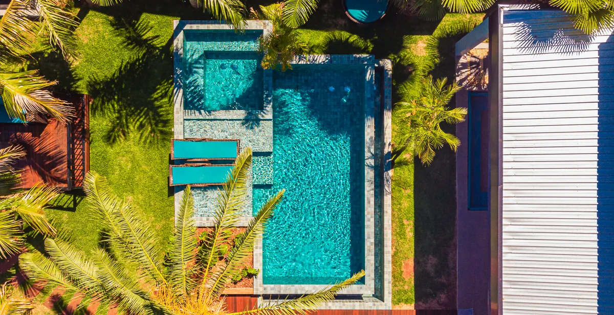 Vista aérea vertical revelando a geometria retangular da piscina, do spa e das plataformas