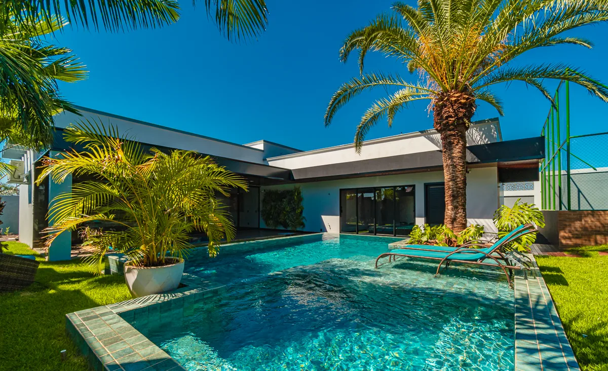 Conjunto da piscina com a casa térrea de linhas horizontais ao fundo