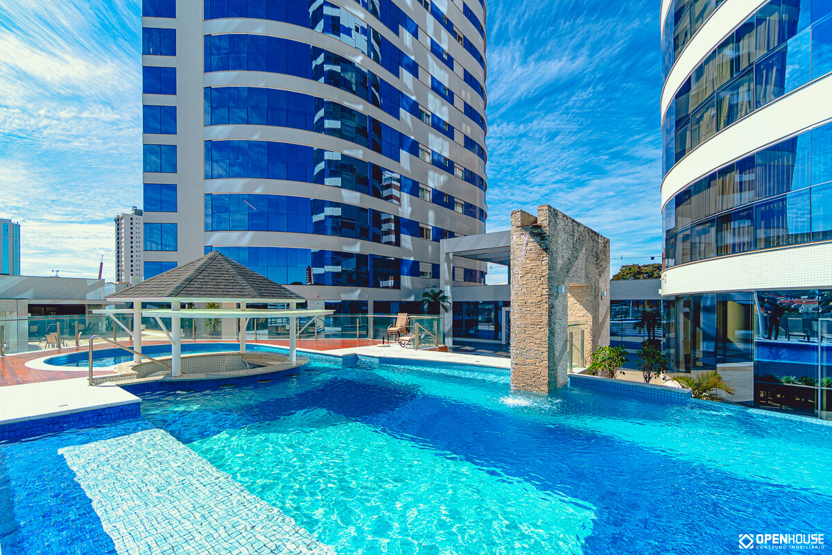 Piscina coletiva com parede de água em pedra entre as torres e o gazebo da área de convivência