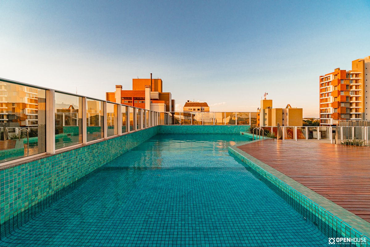 Recorte em ângulo da borda da piscina, com o deck de madeira acompanhando o desenho da lâmina