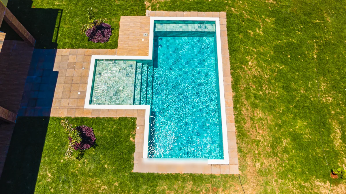 Vista aérea da piscina com a hidromassagem, o deck de madeira e o piso de pedra ao redor