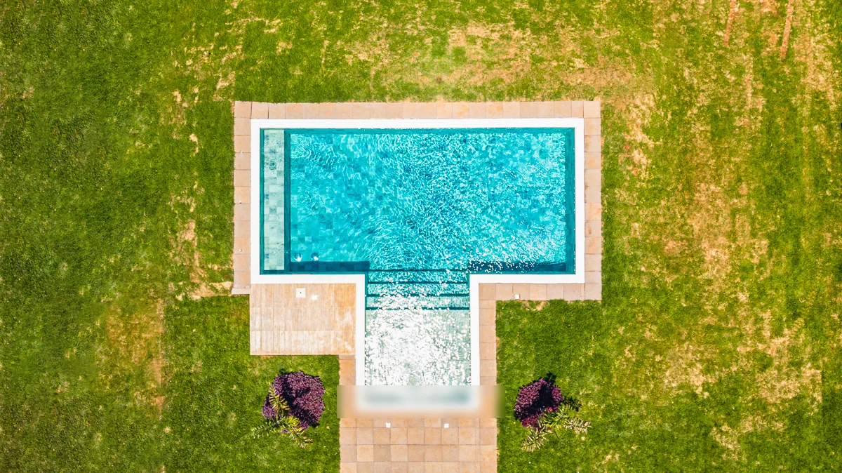Vista aérea vertical mostrando a geometria recortada da piscina, da hidromassagem e do deck