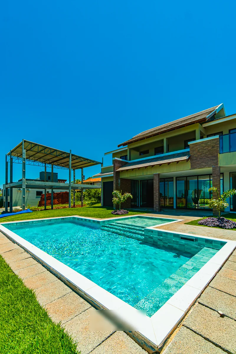 Enquadramento vertical da piscina com a hidromassagem contígua e a residência ao fundo
