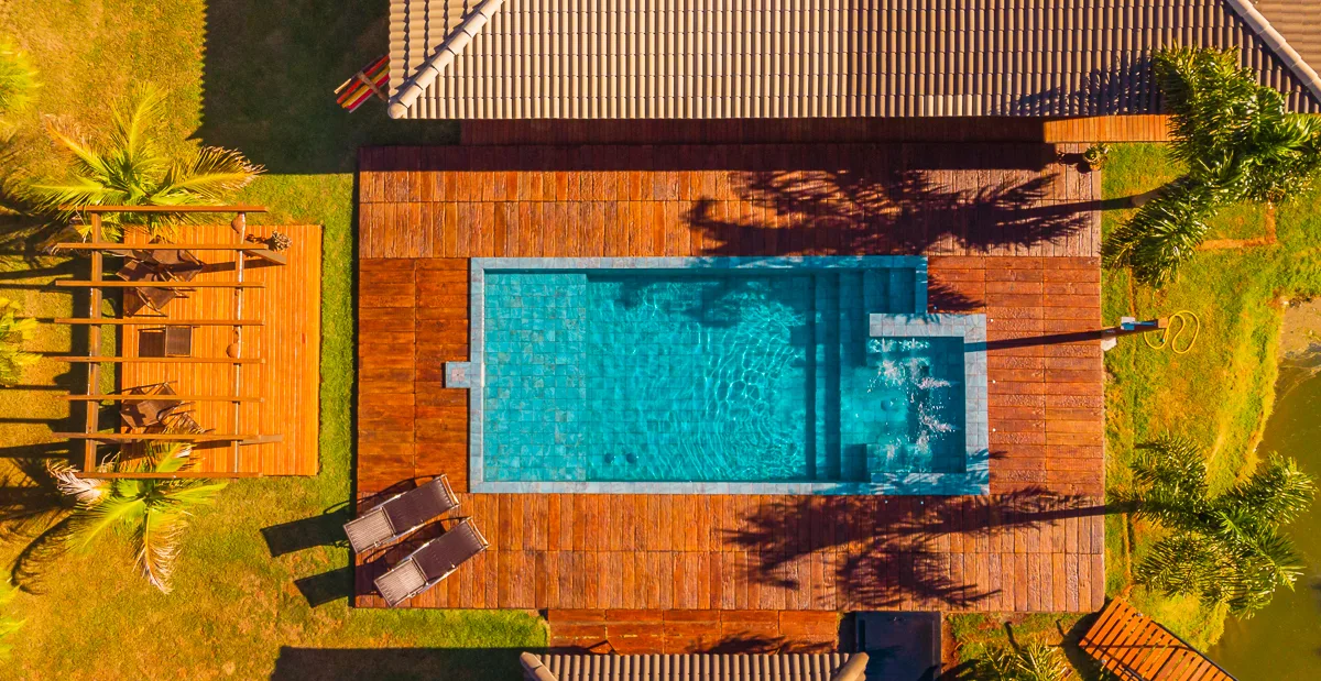 Vista aérea mostrando a hidromassagem, a piscina, o deck de madeira e o lago no entorno da sede