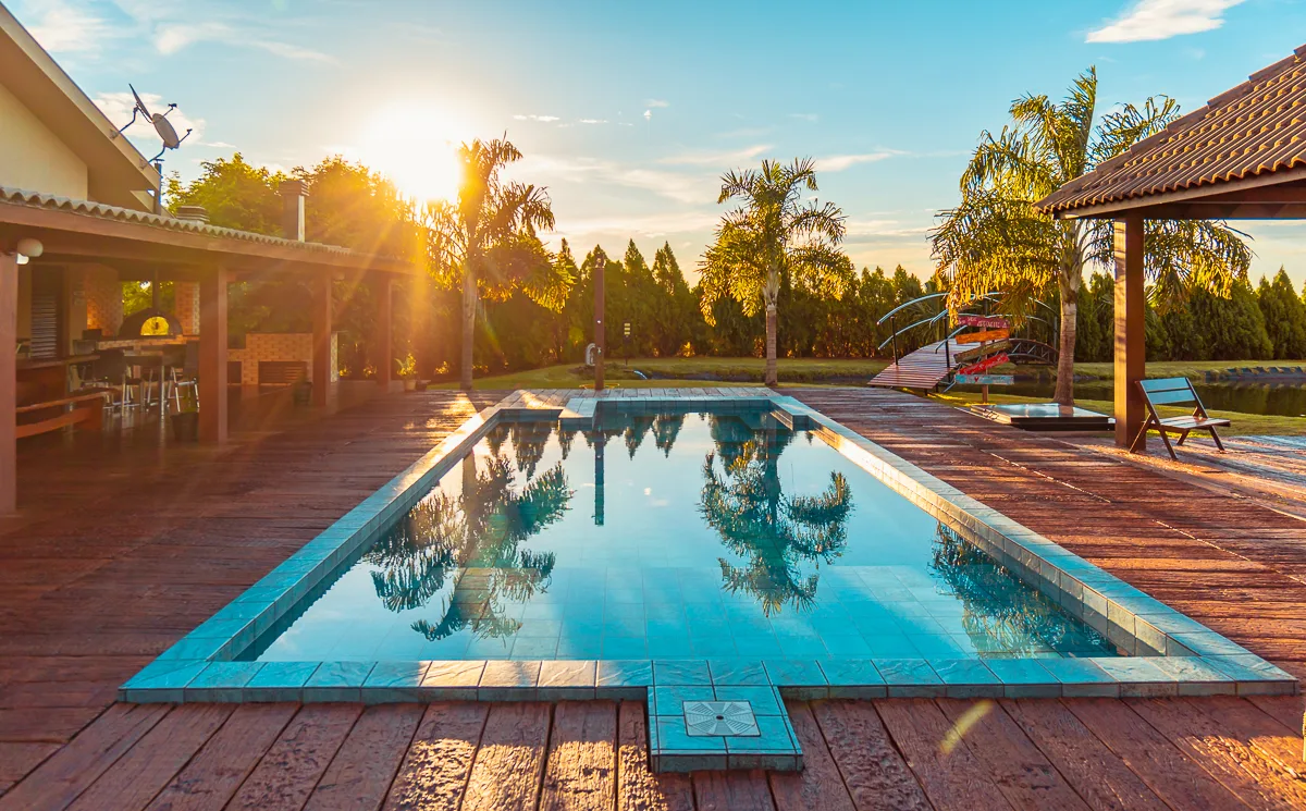 Área lounge com espreguiçadeiras e paisagismo tropical ao lado da piscina