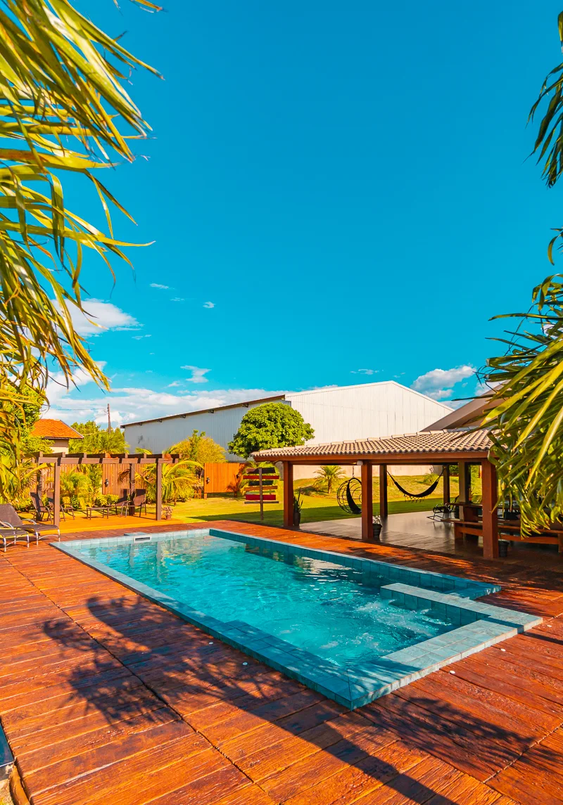 Sede da fazenda com varanda coberta aberta para a piscina e o deck de madeira