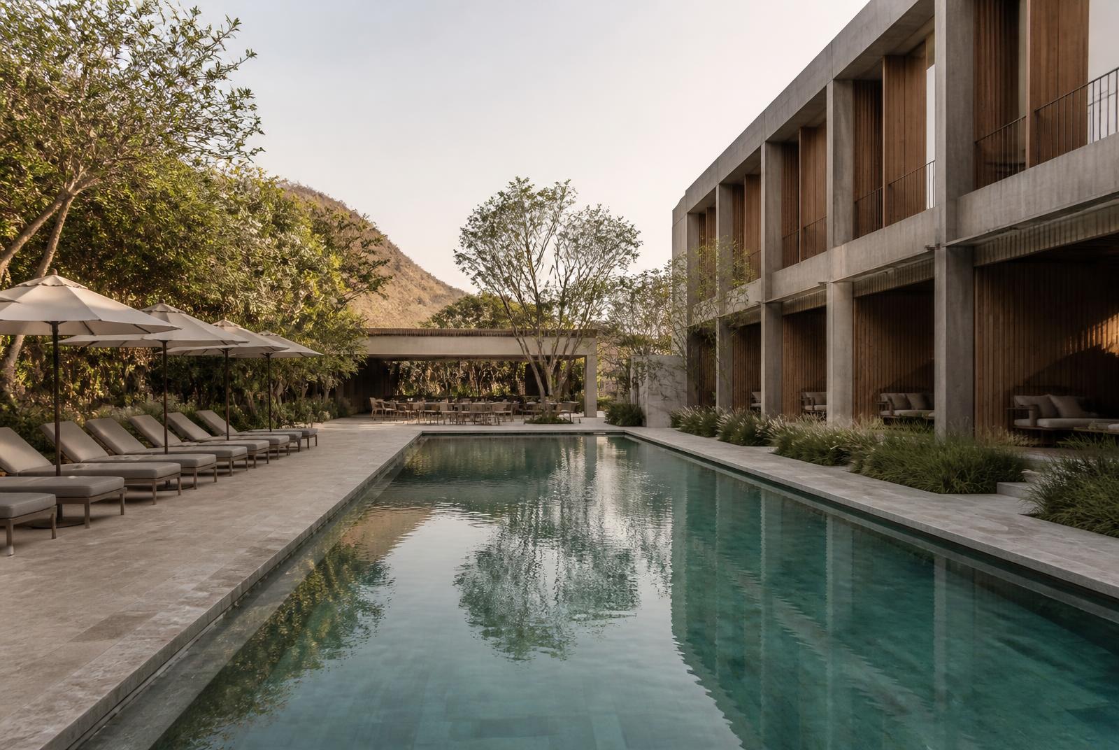 Piscina de hotel contemporâneo com deck em pedra, arquitetura em concreto e madeira e paisagismo discreto