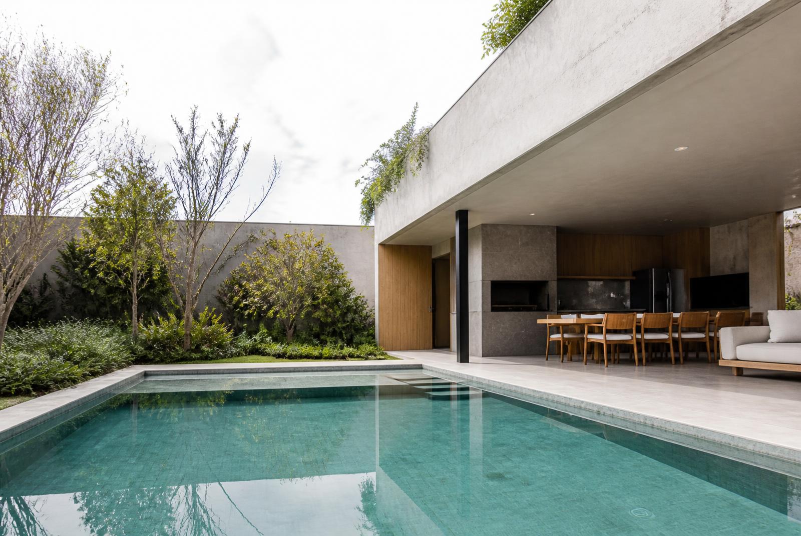 Piscina residencial integrada à área gourmet coberta, com luz natural e materiais neutros